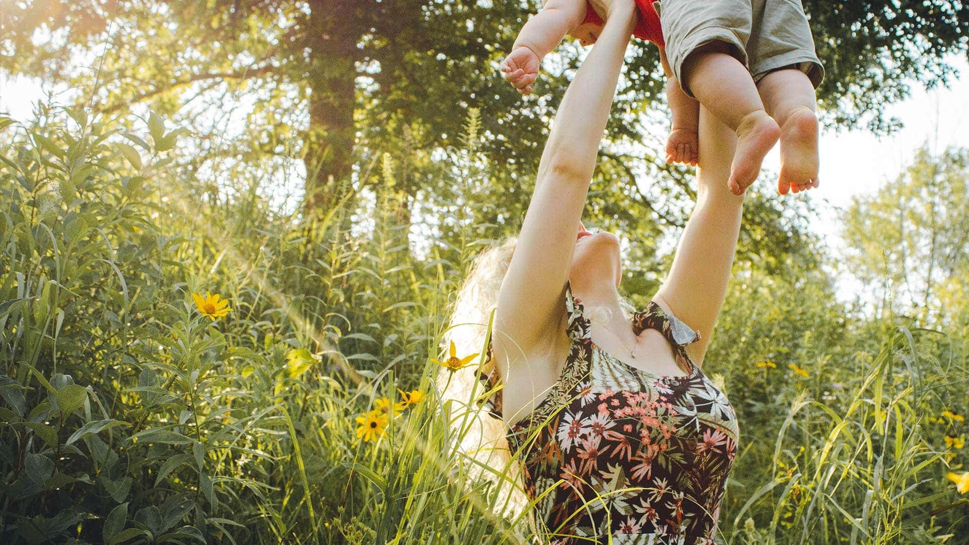 Parent lifting a child in a sunny meadow